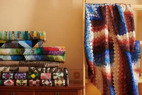 Stack of quilts and quilt made in the bargello style on yellow wall backgroun Stock-Fotos