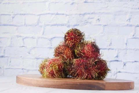 Stack of rambutan in a chopping board on table Stock Photos