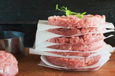Stack of  raw homemade beef burgers on a wooden cutting board. Stock Photos
