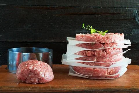Stack of  raw homemade beef burgers on a wooden cutting board with minced meat Stock Photos
