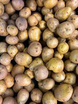Stack of raw potatoes in plastic container in market. Top view Foto stock