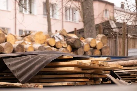 Stack of Raw Timber Planks and Round Wood Logs in Backyard Near House with .. Fotos Stock