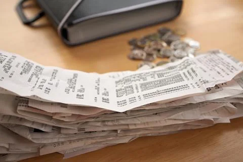 A stack of receipts in the Foreground with Coins and Accordion Folder Organizer Stock Photos