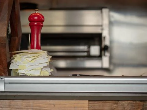 Stack of receipts impaled on a counter next to red pepper grinder on counter Stock Photos
