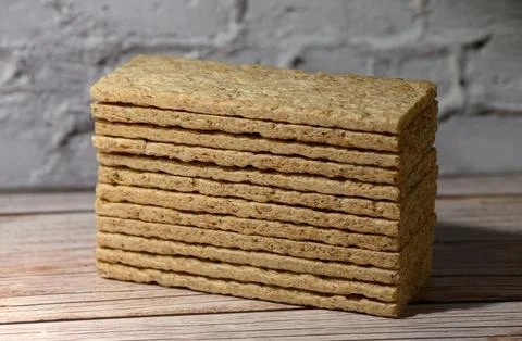 Stack of rectangular crispbread on a wooden surface against a white brick wal Stock Photos