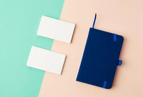 Stack of rectangular white blank business cards and blue notebook on a green  Foto stock
