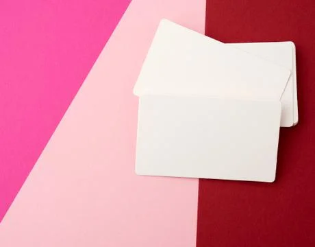 Stack of rectangular white paper blank business cards on a pink background 스톡 사진