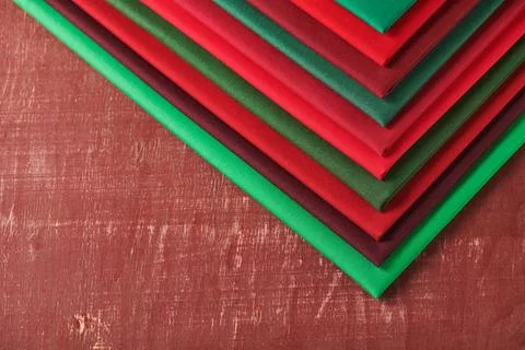 Stack of red and green fabrics on brown background, space for text Stock-Fotos