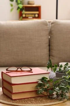 Stack of red books with reading glasses on a woven mat, cozy home interior wi Stock Photos
