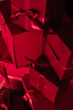 Stack of red boxes tied with red ribbon against red curtain Stock Photos