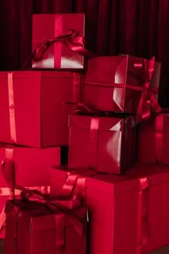 Stack of red boxes tied with red ribbon against red curtain 写真素材