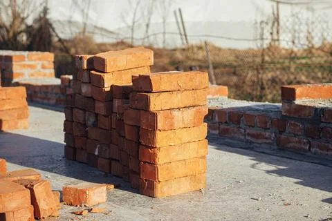 Stack of red bricks on concrete foundation, process of house building. Buil.. Stock Photos