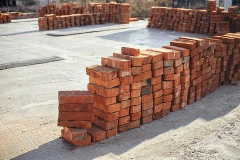 Stack of red bricks on concrete foundation. Building materials at construct.. Stock Photos