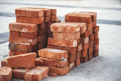 Stack of red bricks on concrete foundation, process of house building Stock Photos