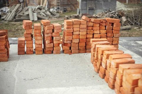 Stack of red bricks on concrete foundation, process of house building Stock Photos