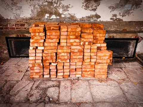 Stack of red bricks in front of weathered wall 写真素材