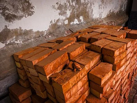 Stack of red bricks in the old house backyard in front of weathered wall Stock Photos