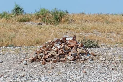 Stack of red bricks rests on dry, rocky ground Stock Photos