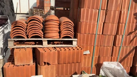 Stack of red clay bricks and roof tiles on wooden pallets in construction yar Stock Footage 324811061