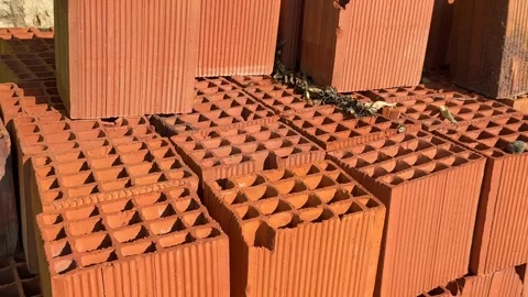 Stack of red clay bricks arranged in sunlight with scattered dry leaves, co.. Stock Footage 328585481