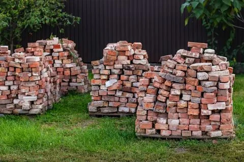 A stack of red clay bricks on a grass Stock Photos
