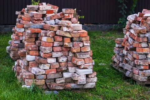 A stack of red clay bricks on a grass Foto stock