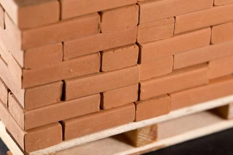 Stack of red clay bricks neatly arranged on a wooden pallet Stock Photos