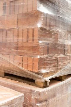 Stack of  Red clay Ceramic Bricks over Euro pallets, construction site, wrapp Stock Photos
