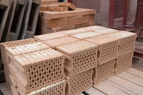 Stack of Red clay Ceramic Bricks over Euro pallets, construction site 库存照片