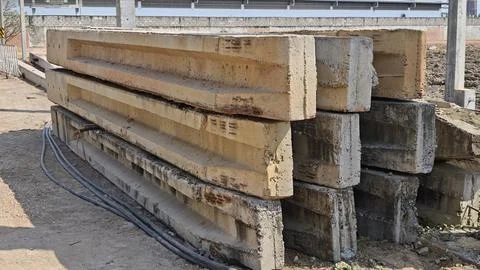 Stack of reinforced precast concrete foundation piles lying on ground. Stock Photos