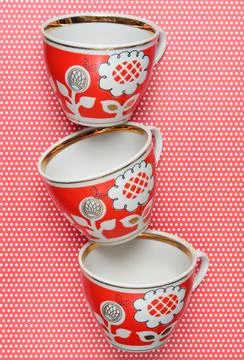 Stack of retro cups with red patterns on a tablecloth whith polka dots. Stock Photos
