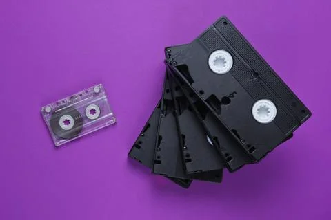 Stack of retro video and audio cassettes on purple background. Top view 库存照片