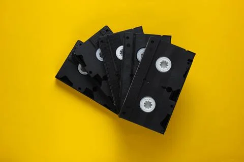 Stack of retro video cassettes on yellow background. Top view Stock Photos