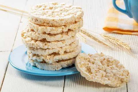 A stack of rice biscuits on a blue saucer and ears of barley on a wooden tabl Stock Photos