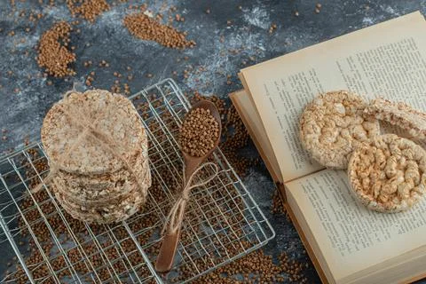 Stack of rice cakes, buckwheat and book on marble surface Stock Photos