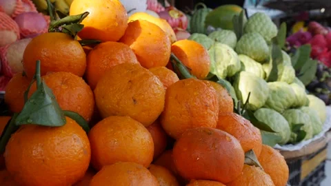 A stack of ripe tangerines glows orange in natural light, some with green leaves Stock Footage 312213877