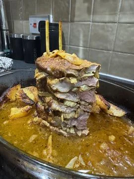 Stack of roasted meat with potatoes in tray cooked in rich sauce Stock Photos