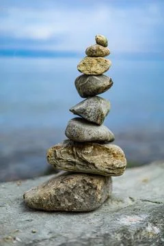 A stack of rocks on a rock by the water Stock Photos