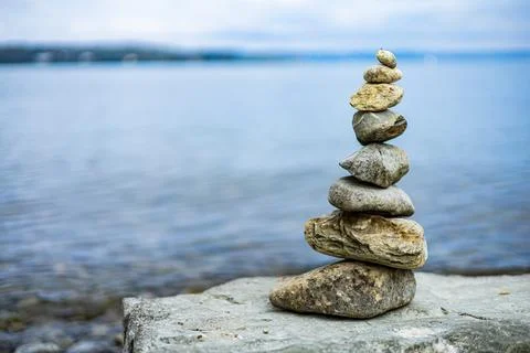 A stack of rocks on a rock by the water Stock Photos