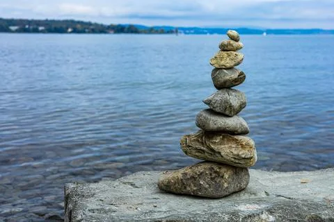 A stack of rocks on a rock by the water Stock Photos