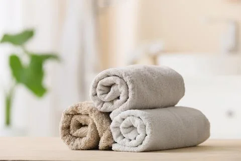 Stack of rolled beige and gray towels on wooden surface Stock Photos