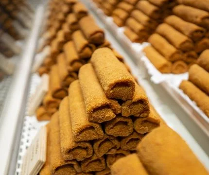 Stack of rolled pastries coated with sugar on display at a bakery counter. Stock Photos