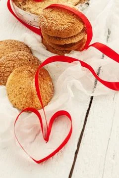 A stack of round biscuits and a red ribbon in the shape of a heart on a whi.. Stock-Fotos