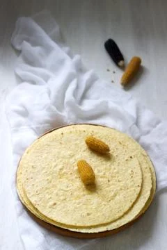 A stack of round corn tortillas on a wooden board and corncobs. Stockfoto's