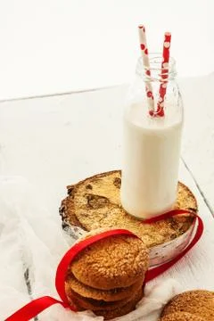 A stack of round shortbread cookies and a bottle of milk, on a white rustic.. Stock-Fotos