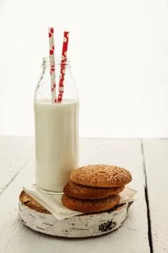 A stack of round shortbread cookies and a bottle of milk, on a white rustic.. Stock-Fotos