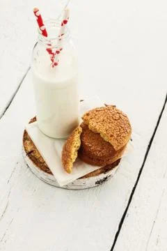 A stack of round shortbread cookies and a bottle of milk, on a white rustic b Foto stock