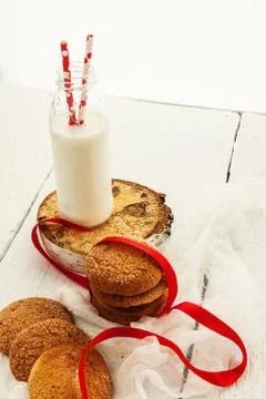 A stack of round shortbread cookies and a bottle of milk, on a white rustic b Stock Photos