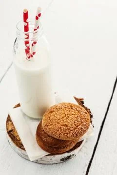 A stack of round shortbread cookies and a bottle of milk, on a white rustic b Stock-Fotos