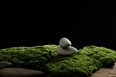 Stack of round stones on green moss, black background. Podium to showcase pro Stockfoto's